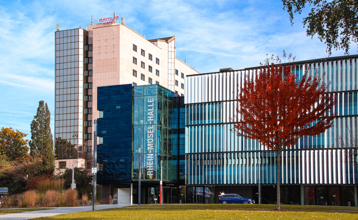 Rhein-Mosel-Halle © Johannes Bruchhof Rhein-Mosel-halle von der Vorderseite mit rotem Baum auf dem Rasen © Johannes Bruchhof