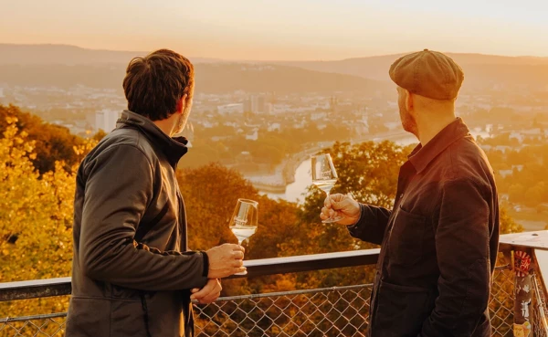 Zwei Männer von der Seite halten Weingläser und blicken auf die Stadt Koblenz beim Sonnenuntergang © Koblenz-Touristik GmbH, Philip Bruederle Zwei Männer von der Seite halten Weingläser und blicken auf die Stadt Koblenz beim Sonnenuntergang © Koblenz-Touristik GmbH, Philip Bruederle