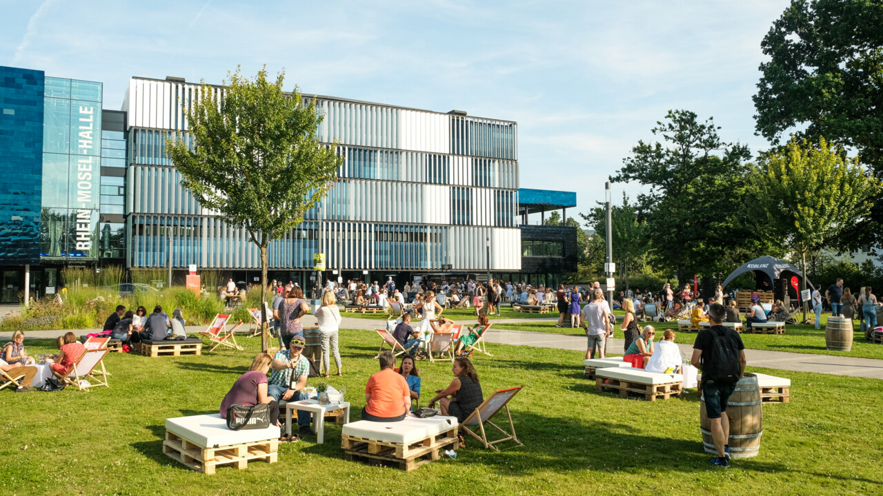 Blaue Stunde Rhein-Mosel-Halle © Camaze Menschengruppen sitzen verteilt bei der Blaue Stunde vor der Rhein-Mosel-Halle © Camaze